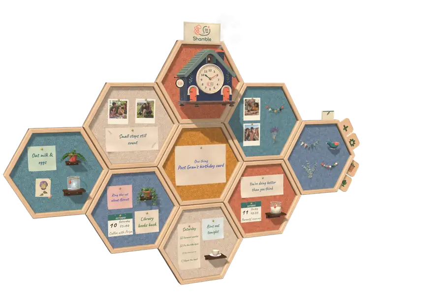 The Shamble board floating and slowly turning: felt hexagons in pine frames holding the One Thing card, notes, photos, calendar pages and the navy clock cottage.